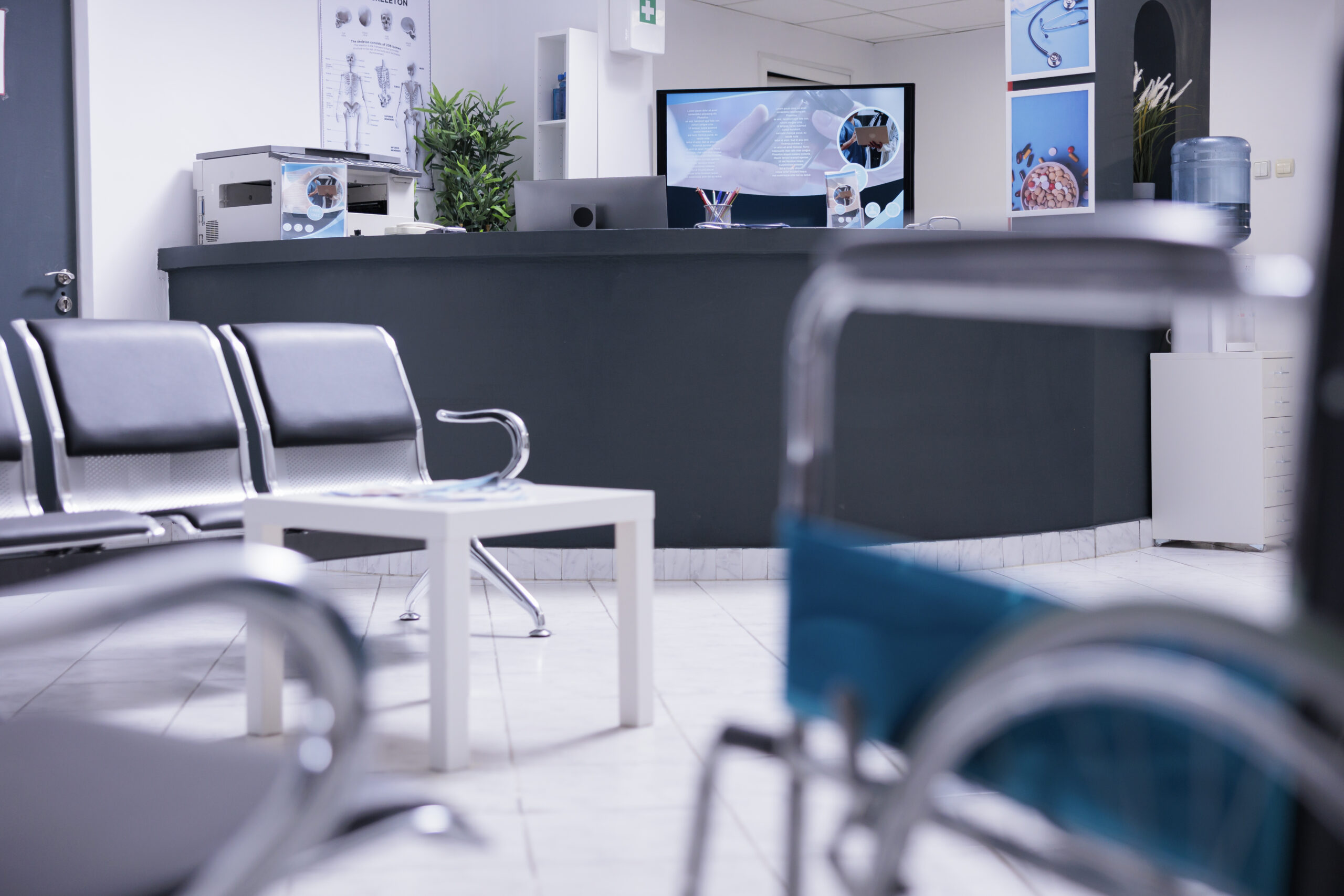 Front desk of medical office reception zone with technological devices, office supplies and medical utilities. Patient reception area with no staff members attending to anyone. Nobody in clinic lobby.